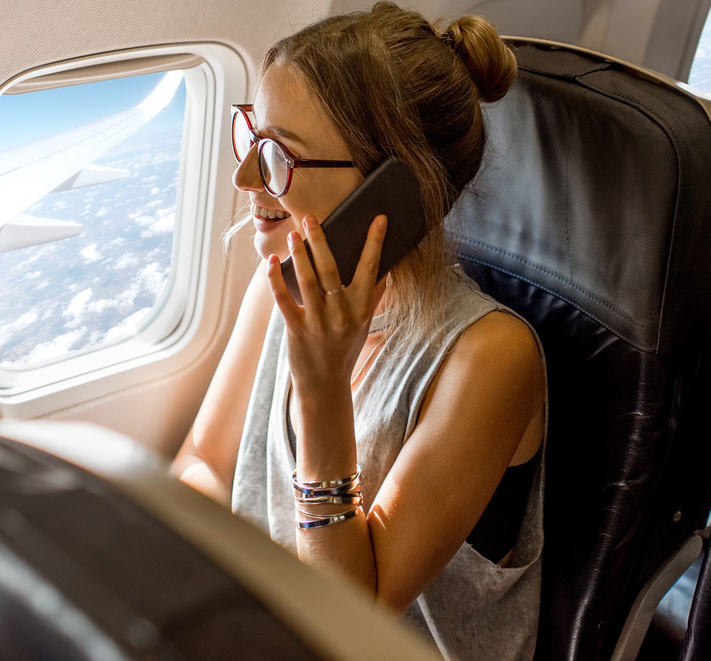 Woman talking on phone inside an airplane.