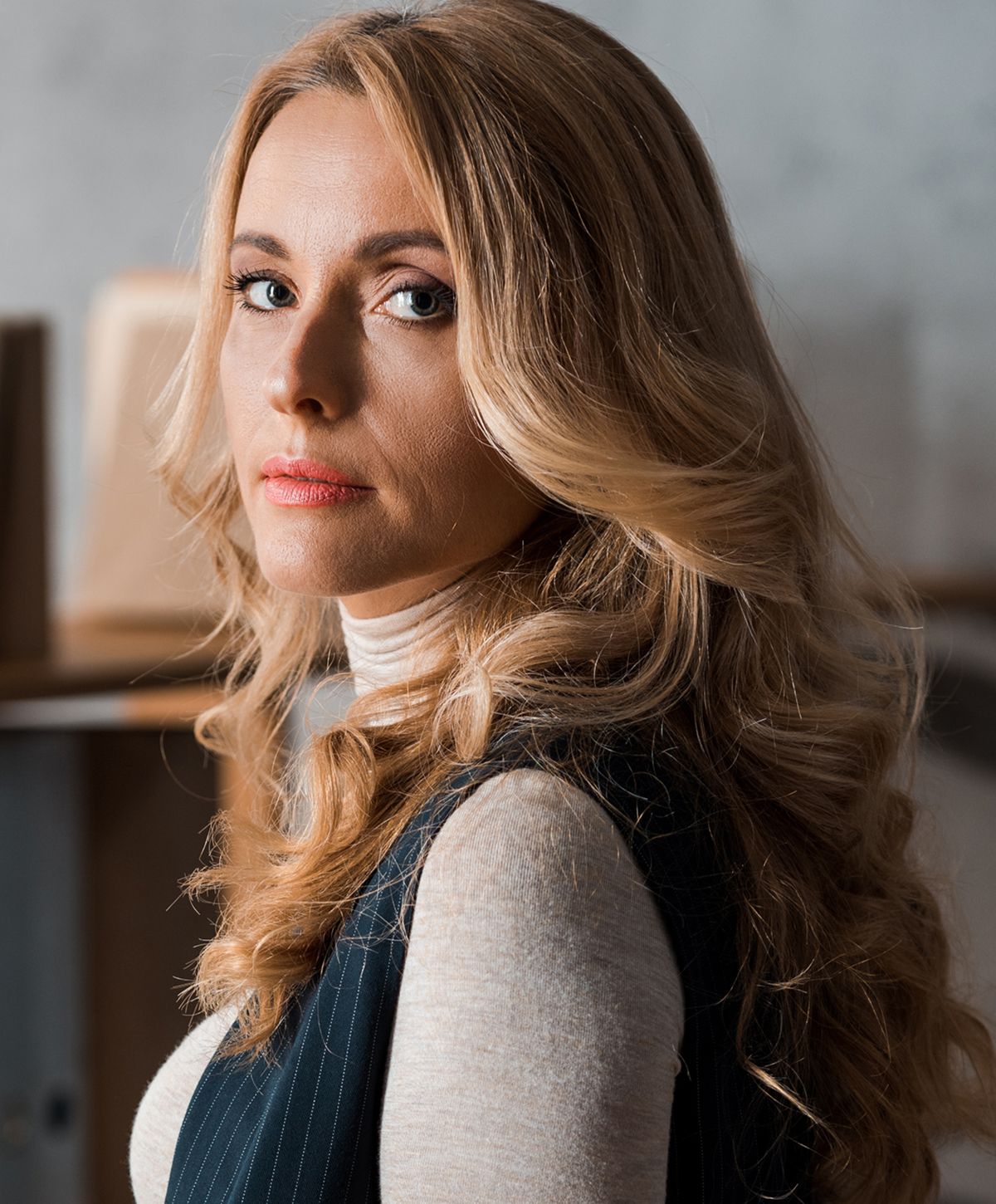 Woman with long, wavy hair and stylish outfit.