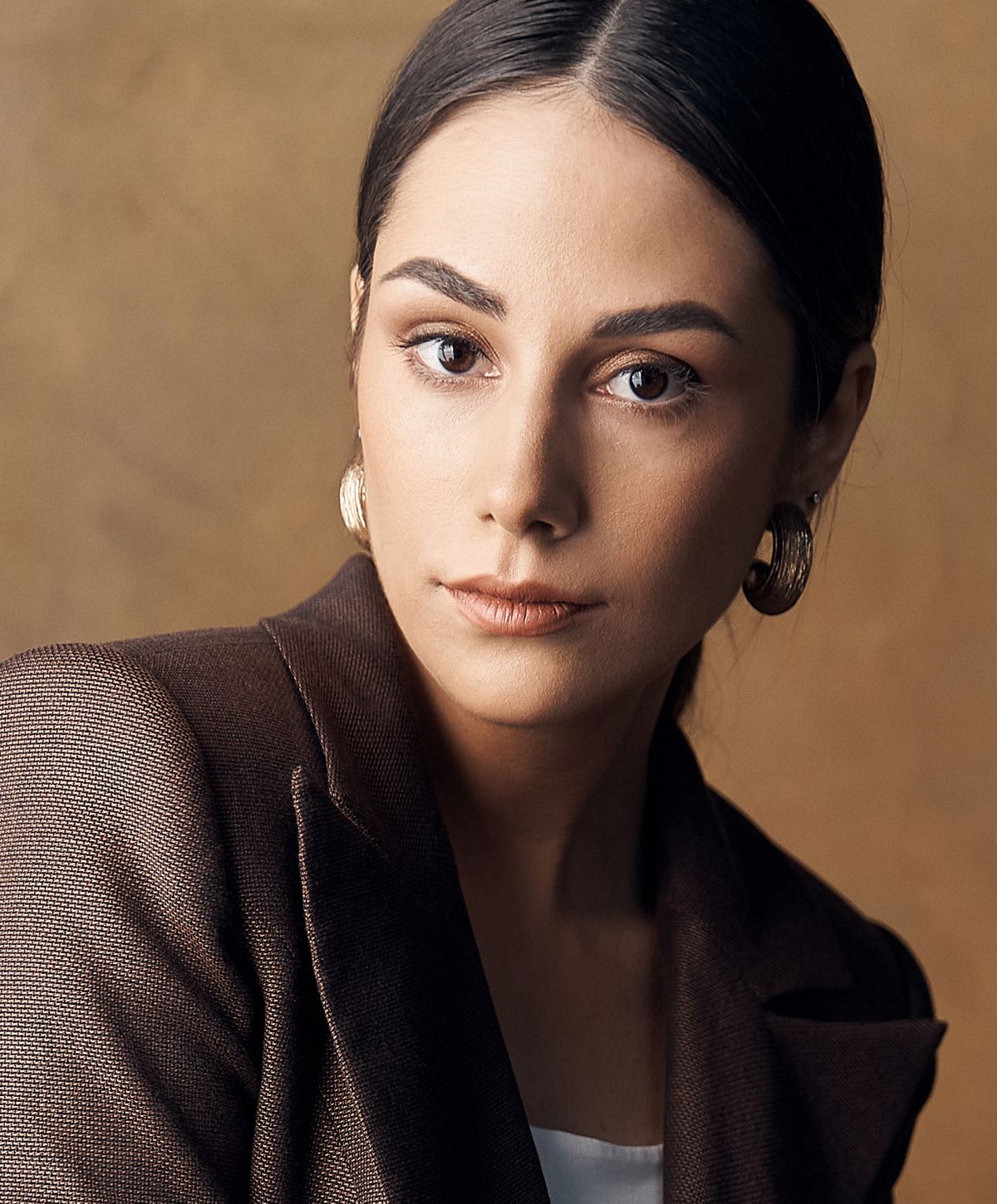 Woman in elegant attire with a neutral background.