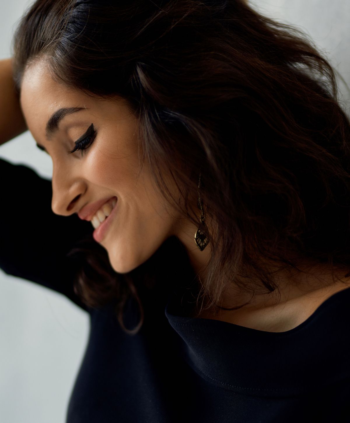 Woman smiling with stylish earrings and tousled hair.