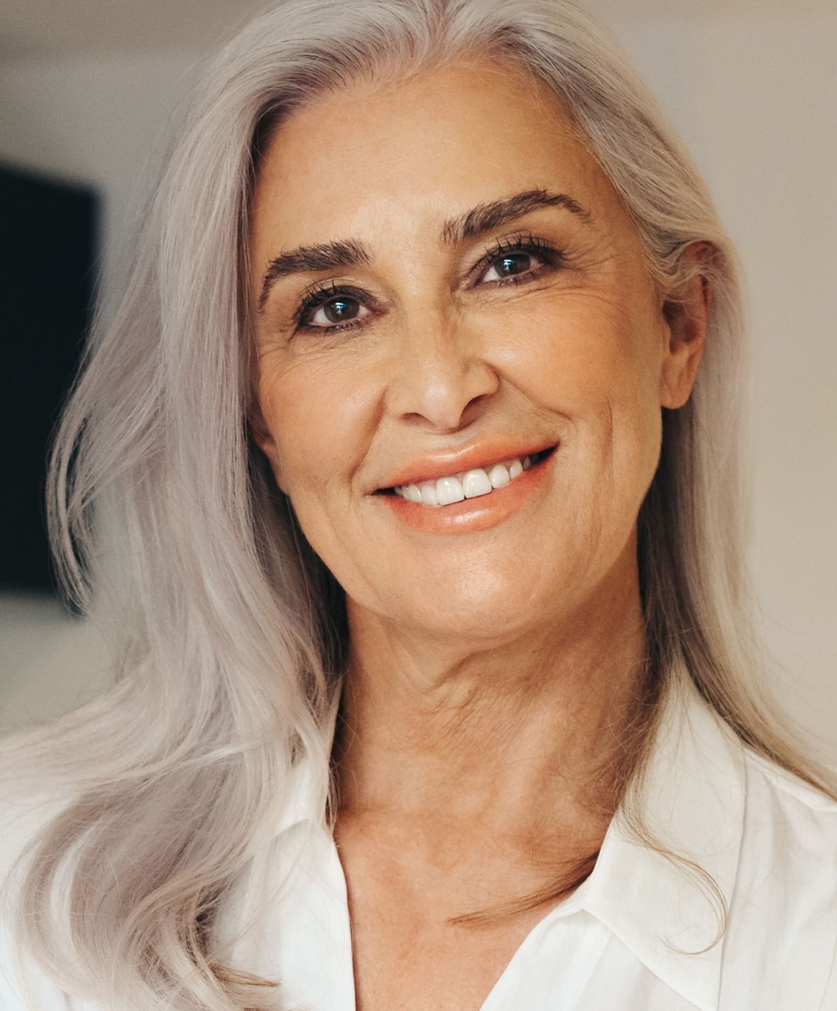 Smiling woman with long silver hair.