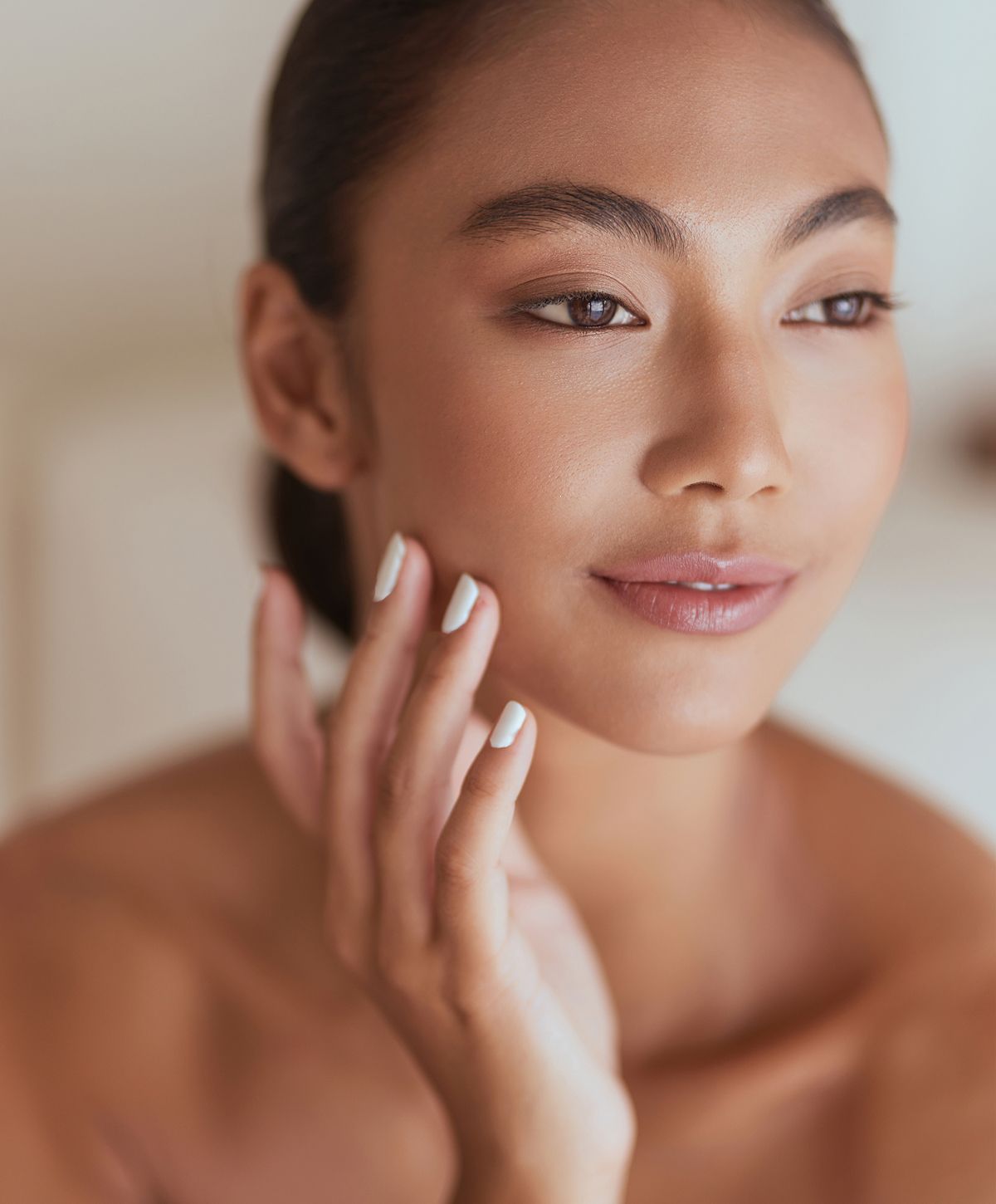 Woman touching her face, natural makeup look.