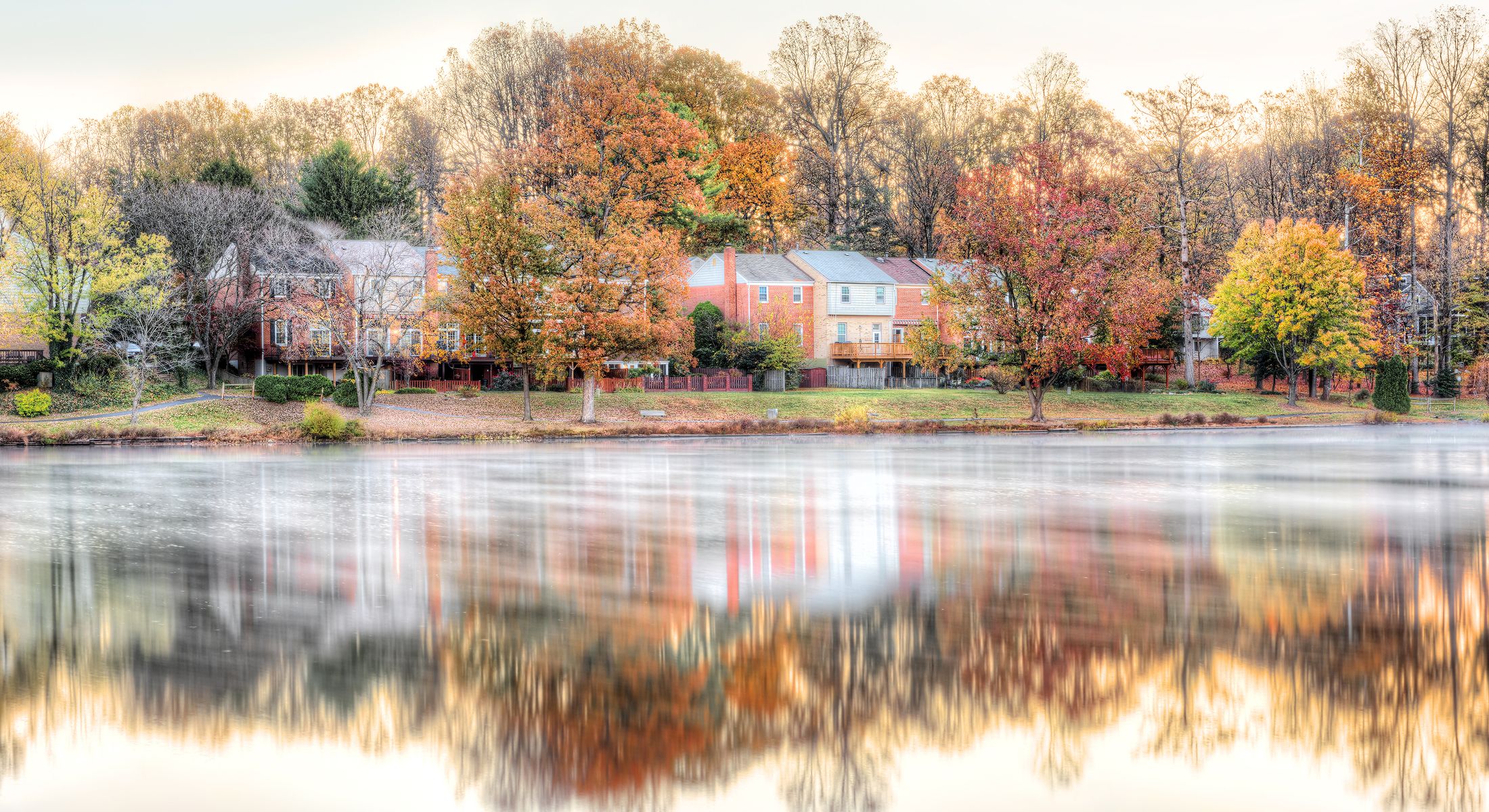 Autumn trees reflected in tranquil lake scene.