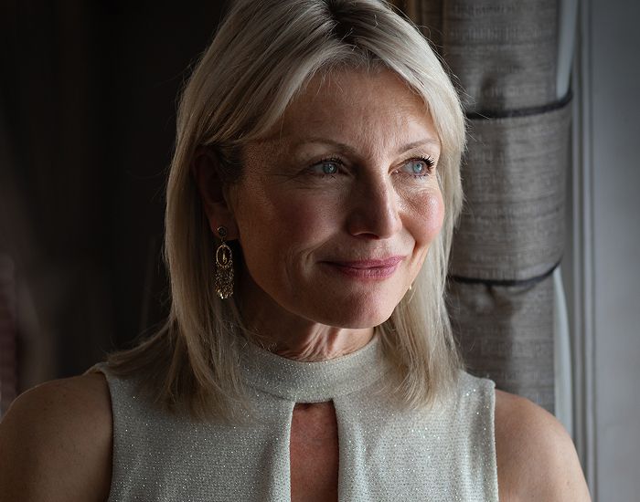 Smiling woman with blonde hair and elegant earrings.