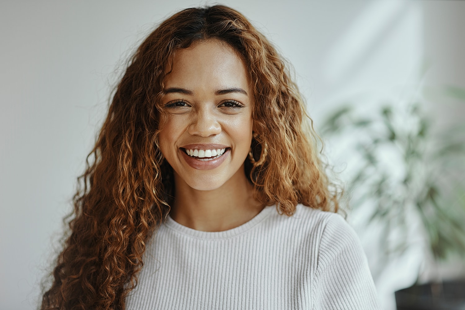 Smiling woman with curly hair in bright setting.