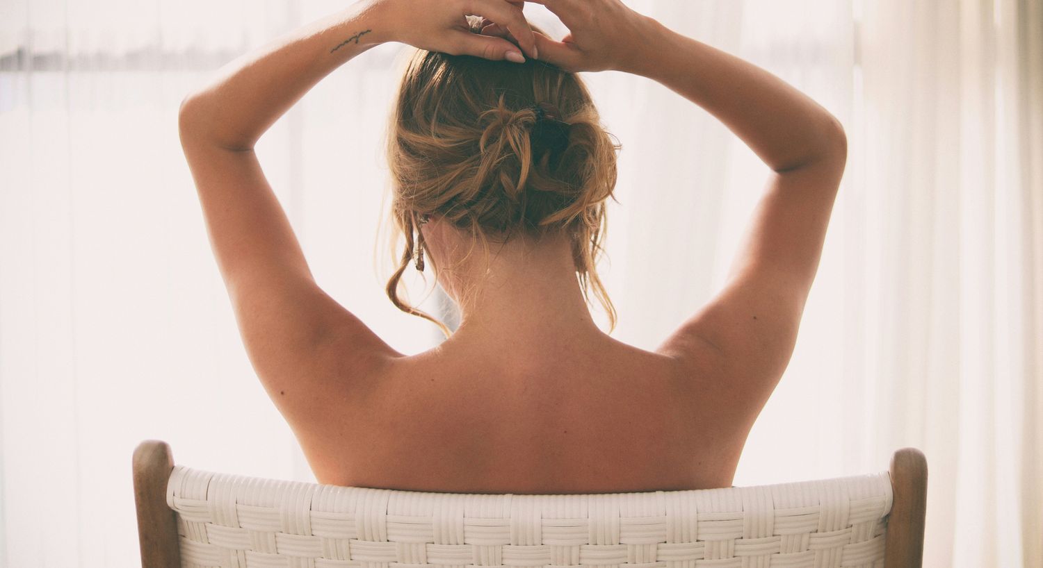 Woman with hair up sitting in chair.
