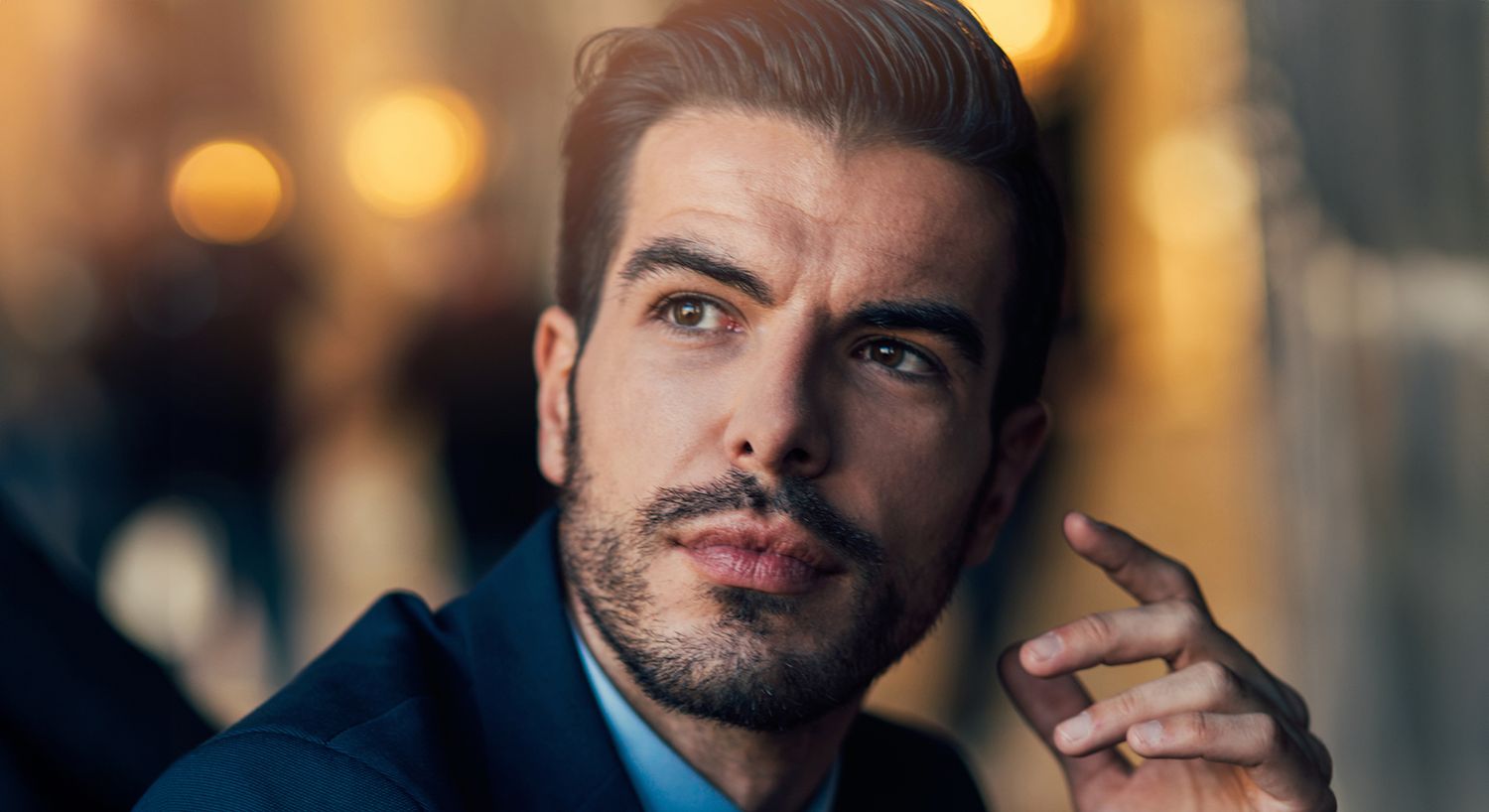 Thoughtful man in suit, blurred background lights.