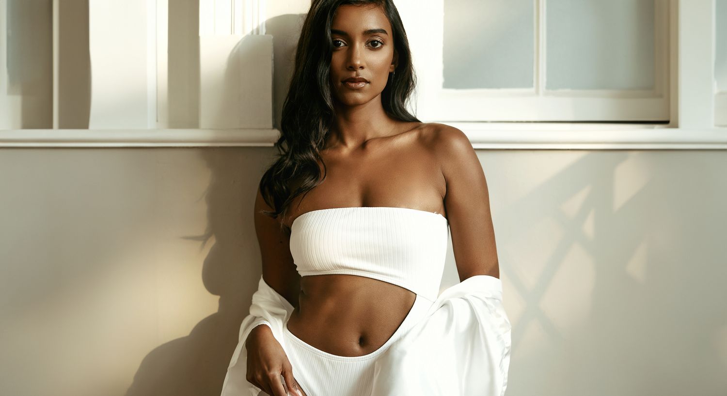 Model posing in white outfit, natural lighting.