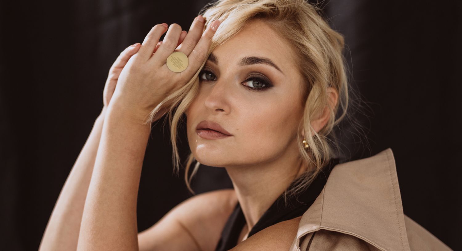 Woman posing elegantly with stylish makeup and attire.