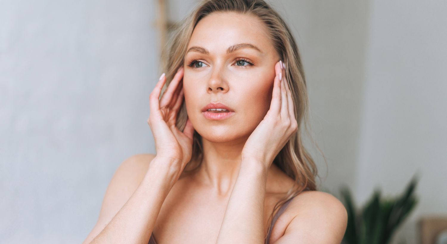Woman gently touching her face, thoughtful expression.