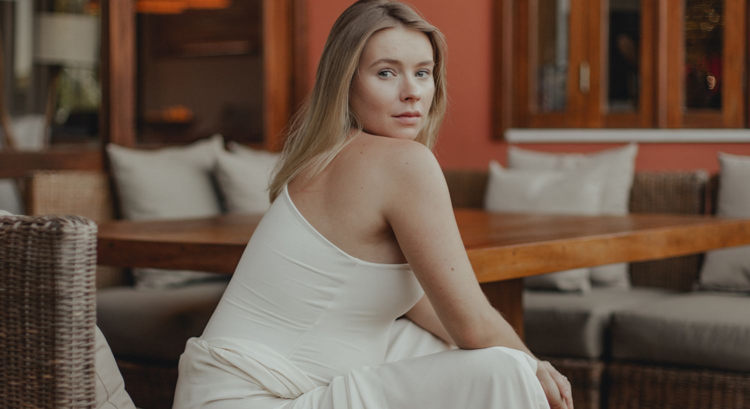Woman in white dress seated at wooden table.