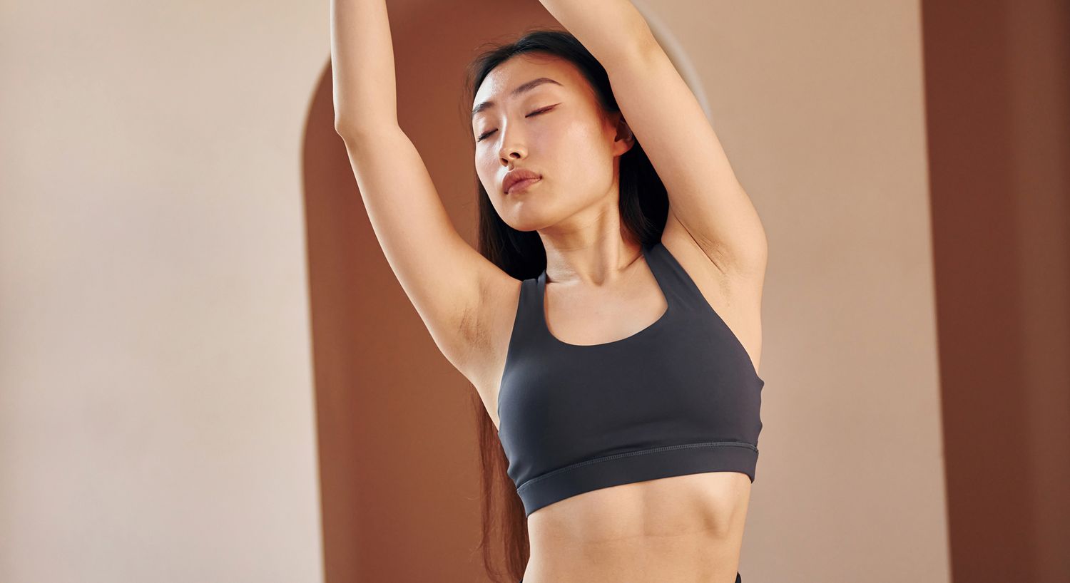 Woman stretching in a sports bra indoors.